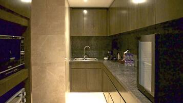 Una cocina moderna con un lavamanos empotrado, una encimera con diversos objetos y un refrigerador.