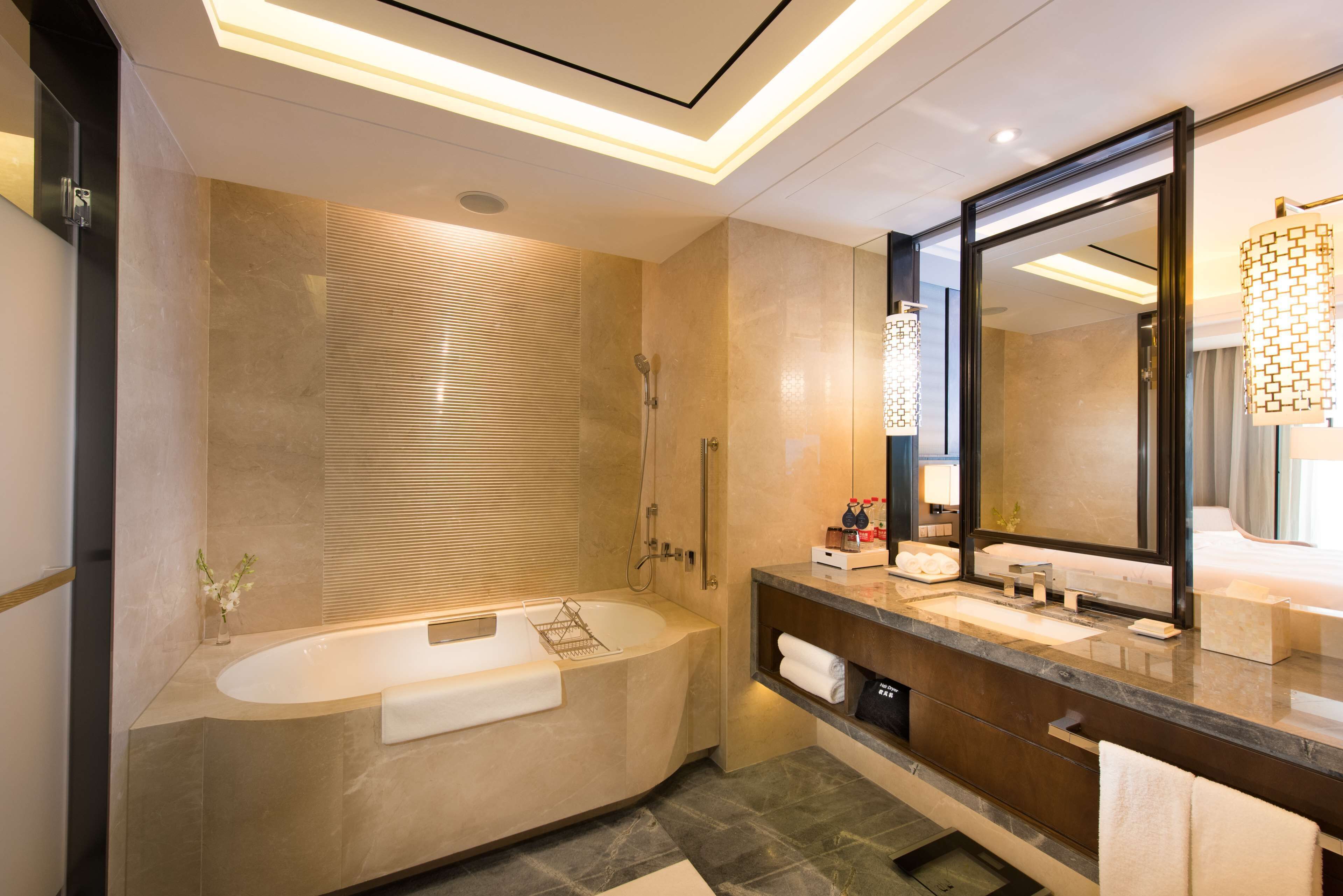 A modern bathroom with a freestanding bathtub, a large mirror, and a vanity with a sink and towel rack.