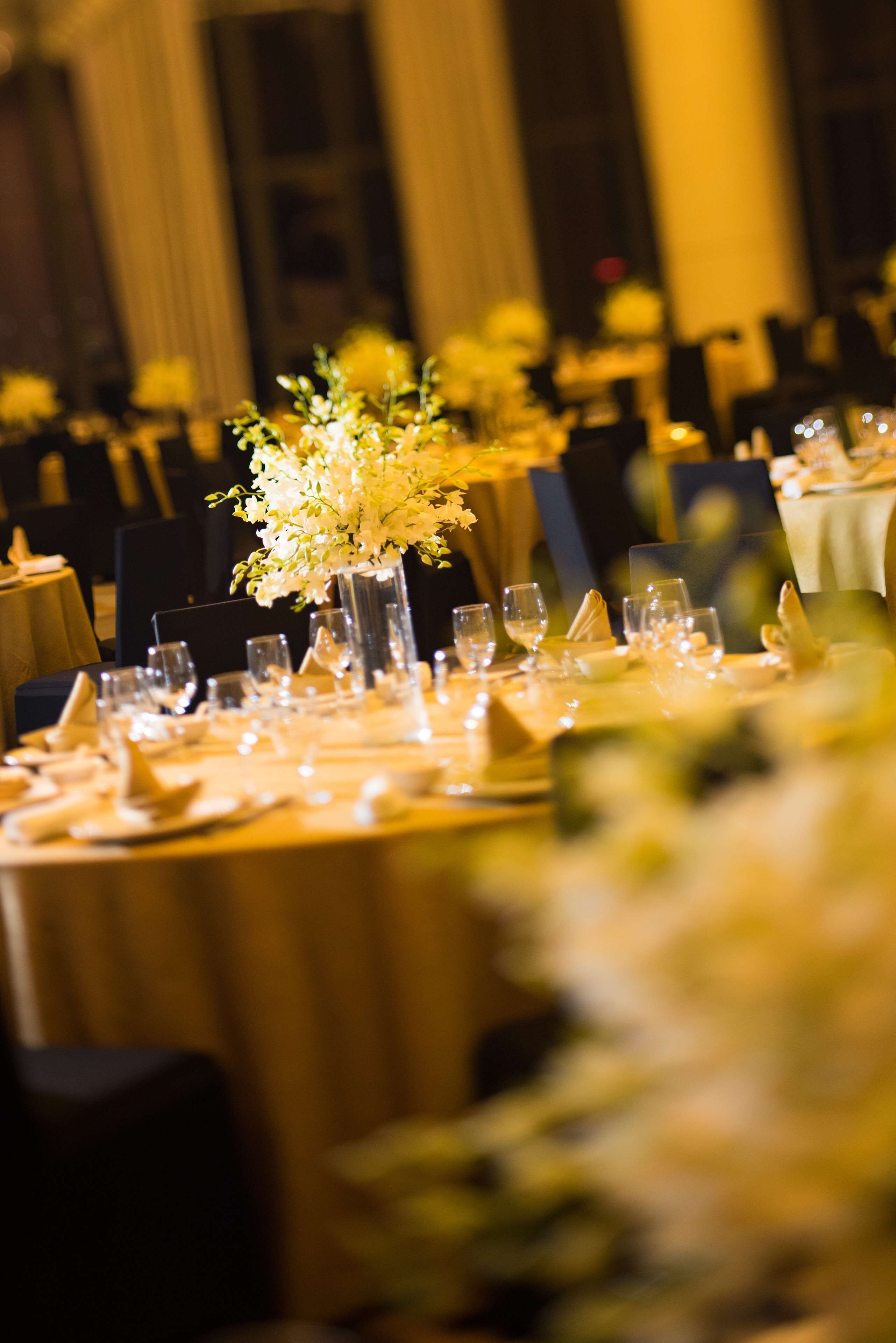 A banquet table set for a formal event with a floral centerpiece, glassware, and folded napkins.
