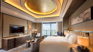 Une chambre d’hôtel moderne dotée d’un grand lit, d’une télévision à écran plat, d’un coin salon et offrant une vue sur l’extérieur.