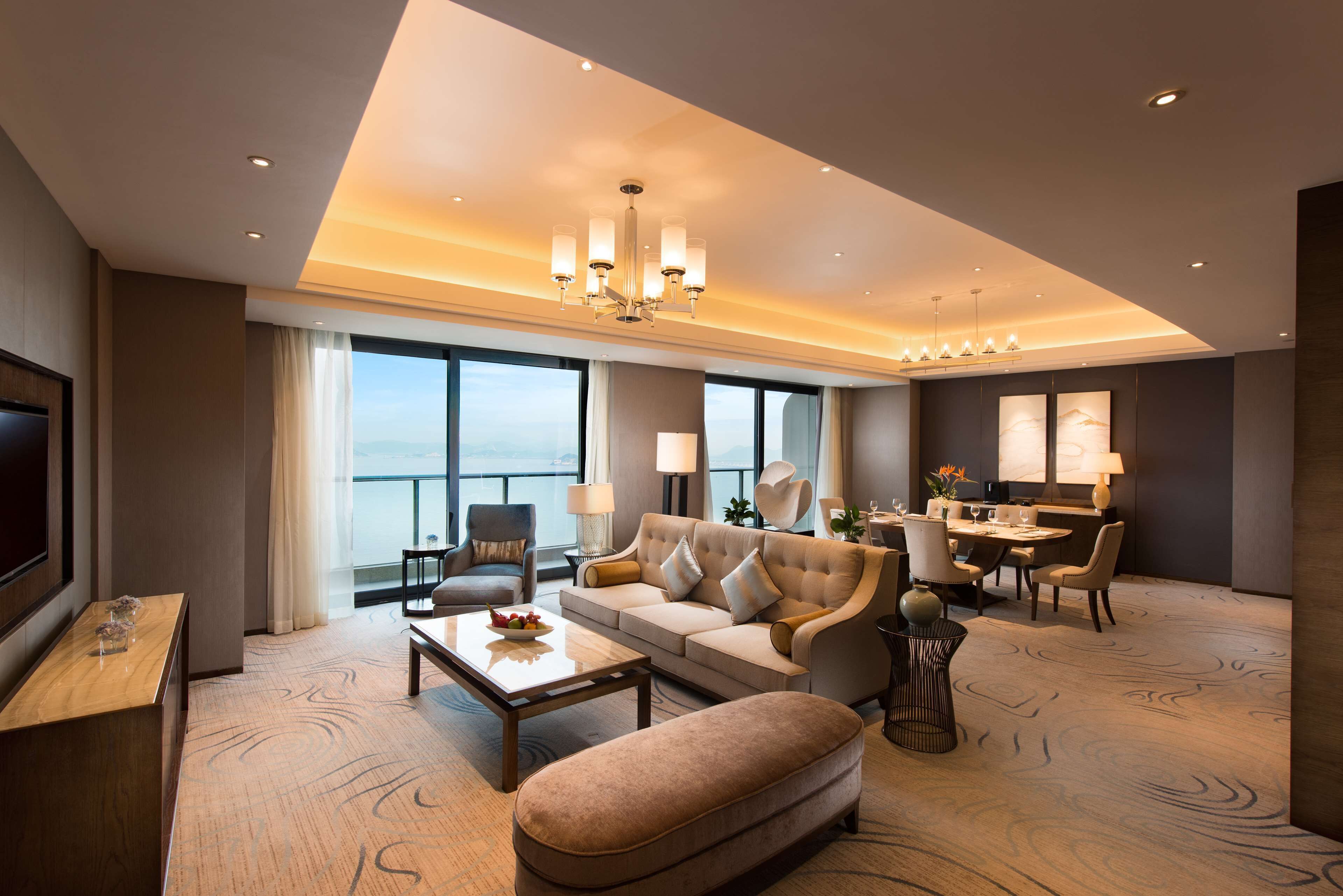 A spacious living room with a large sofa, a coffee table, and a dining area with a table and chairs.