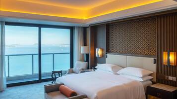 A hotel room with a large bed, a view of the sea, and a balcony.