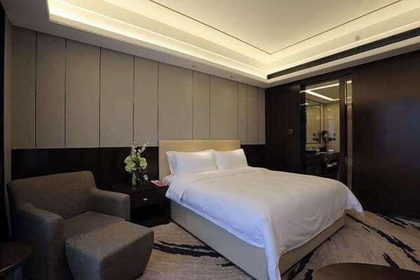 Una camera d'albergo moderna con un letto grande, un'area salotto e uno specchio.