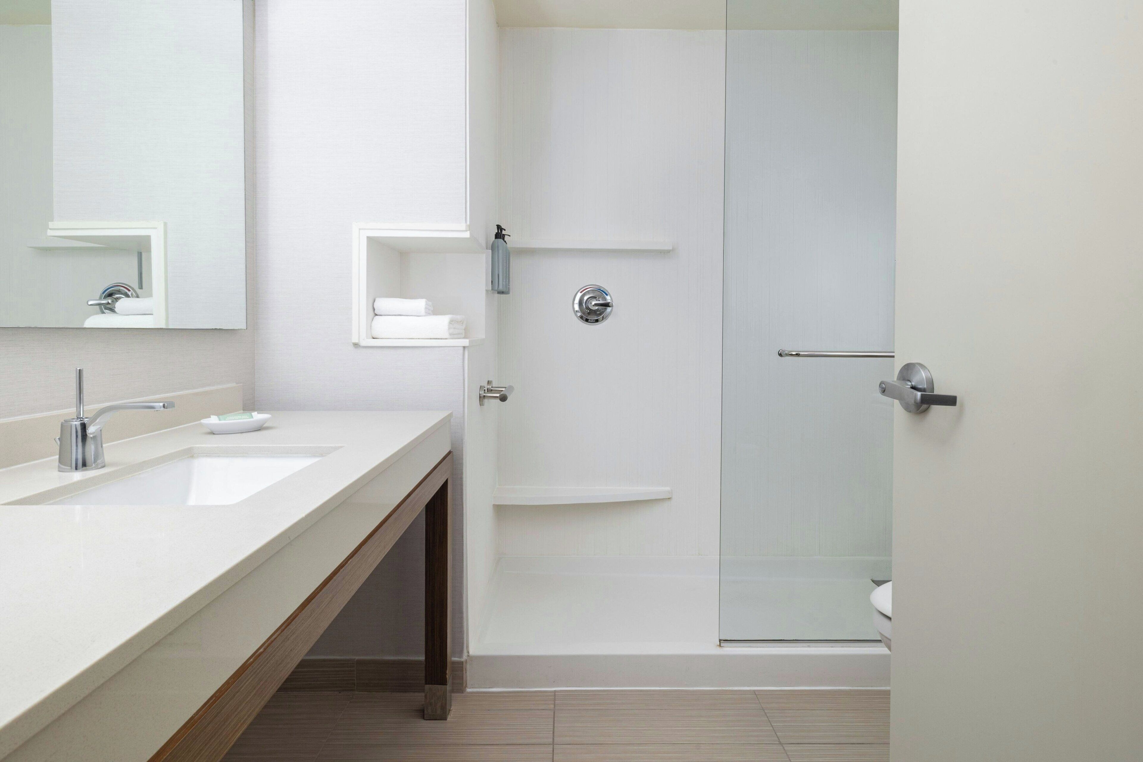 A modern bathroom with a double sink, a glass shower enclosure, and a toilet.