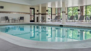 A swimming pool with lounge chairs and a view of trees.