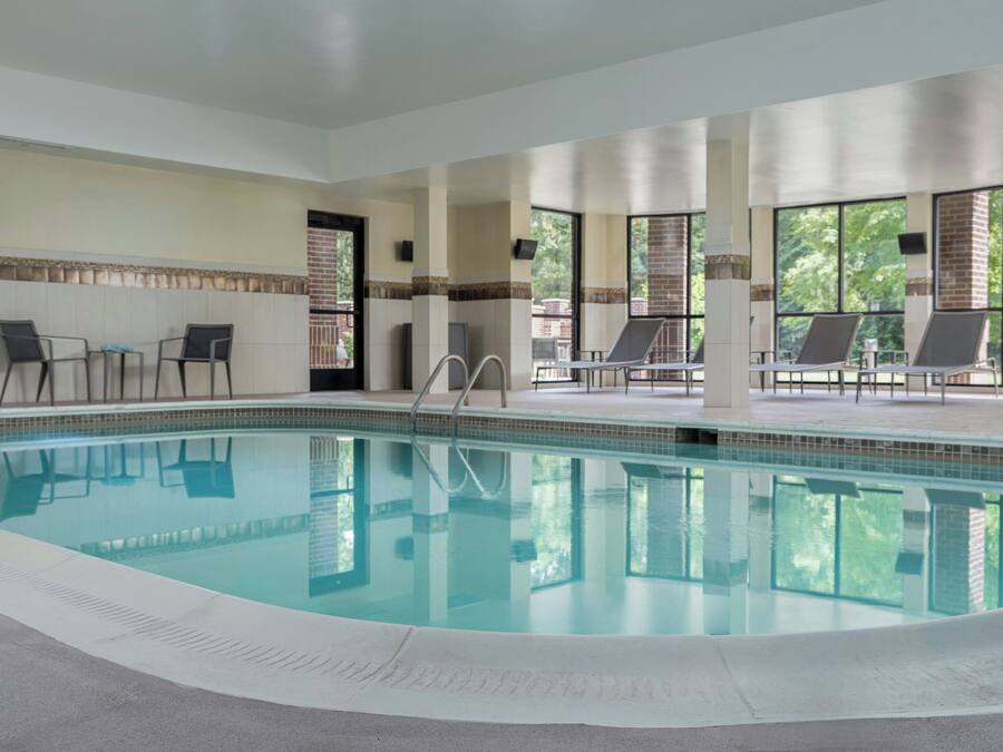 A swimming pool with lounge chairs and a view of trees.