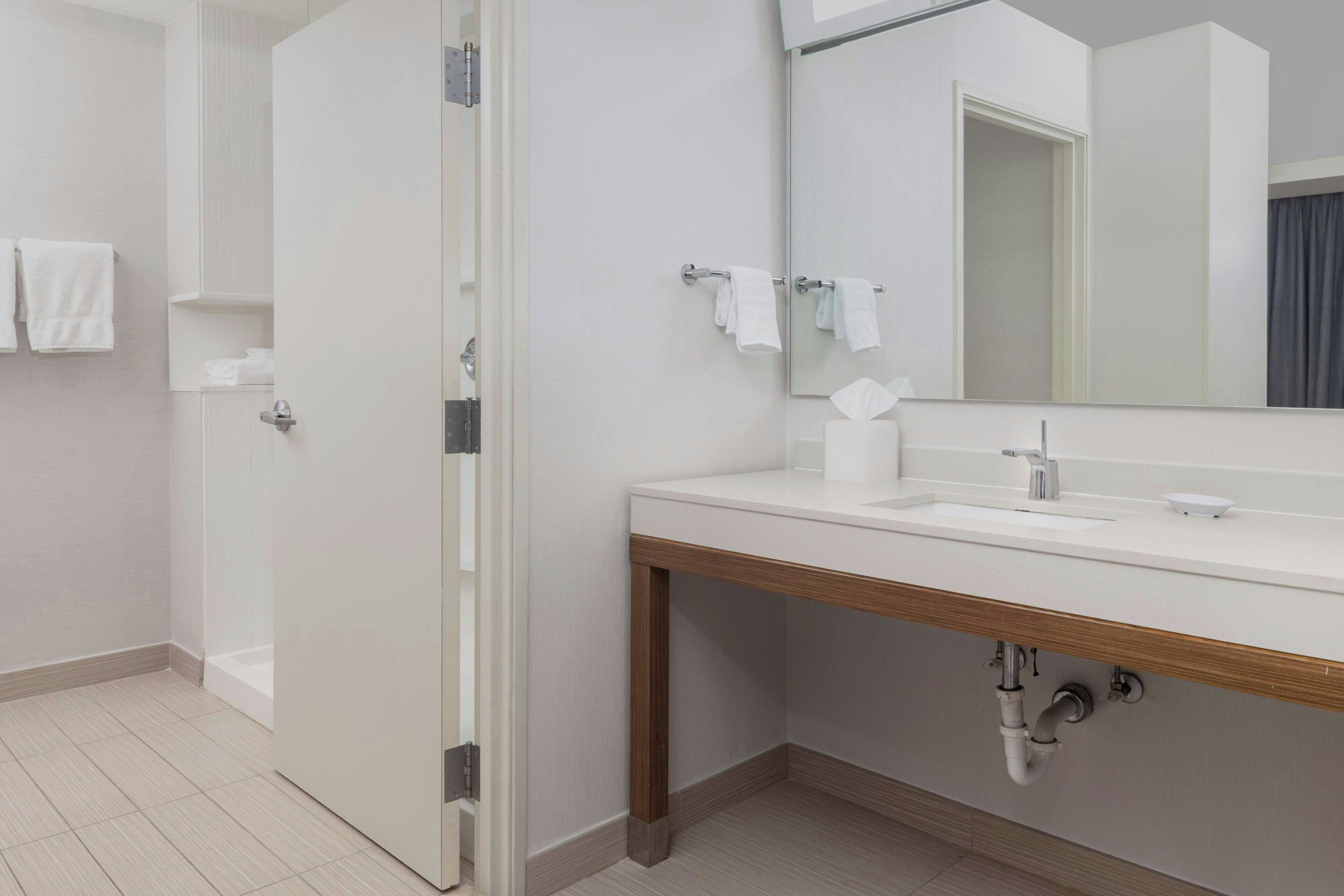 A modern bathroom with a shower, a sink, a mirror, and a toilet.