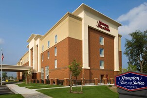 Edificio de Hampton Inn & Suites by Hilton con fachada de ladrillo, varias ventanas y un cartel.