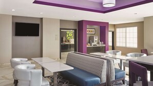 A modern restaurant with a booth seating area, white tables, and a flat-screen TV mounted on the wall.