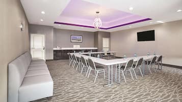 Uma sala de conferências com uma mesa comprida, cadeiras, um sofá e um balcão de recepção.