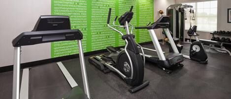 A gym with treadmills, a weight machine, and dumbbells.