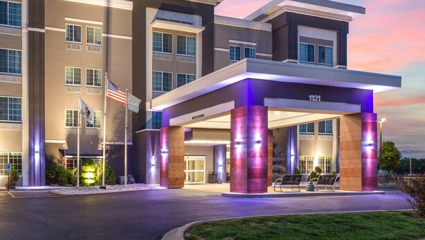 A modern hotel entrance with a covered waiting area, an American flag, and a number '121' sign. - La Quinta Inn & Suites by Wyndham Springfield IL (Springfield)
