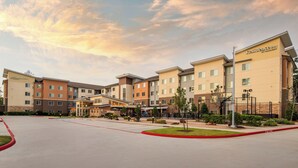 A multi-story hotel with a modern design, featuring a central entrance and multiple units visible. - Residence Inn by Marriott Houston City Place (Spring)