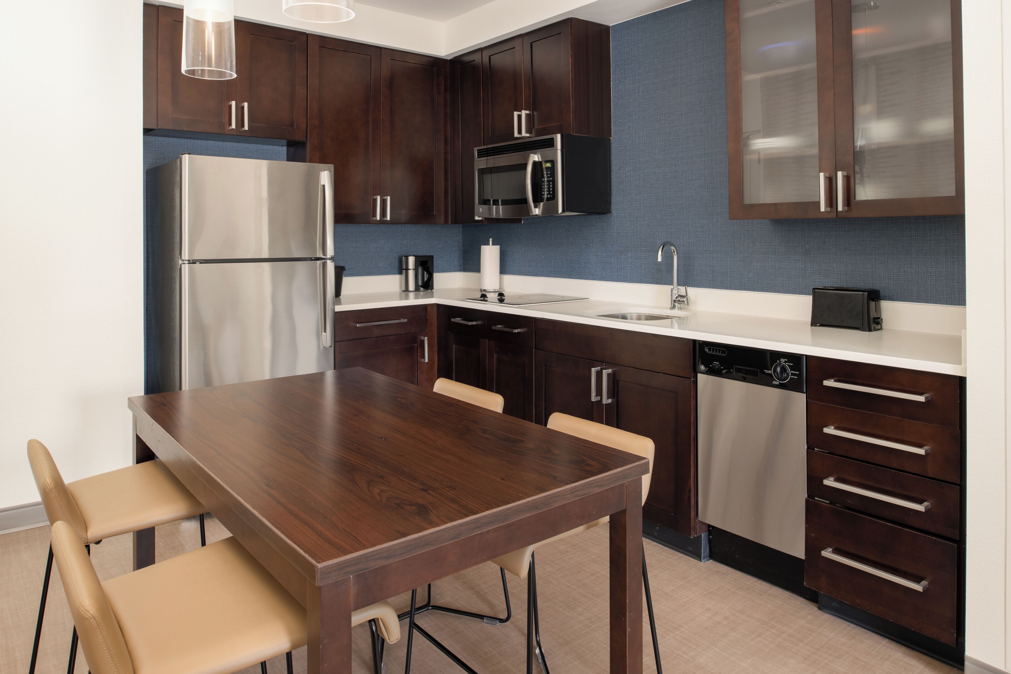 Una cocina moderna con armarios de madera oscura, electrodomésticos de acero inoxidable y una mesa de comedor de madera con sillas.