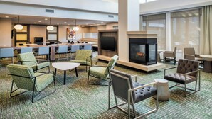 A hotel lobby with a fireplace, seating area, and a bar. - Residence Inn by Marriott Houston City Place (Spring)