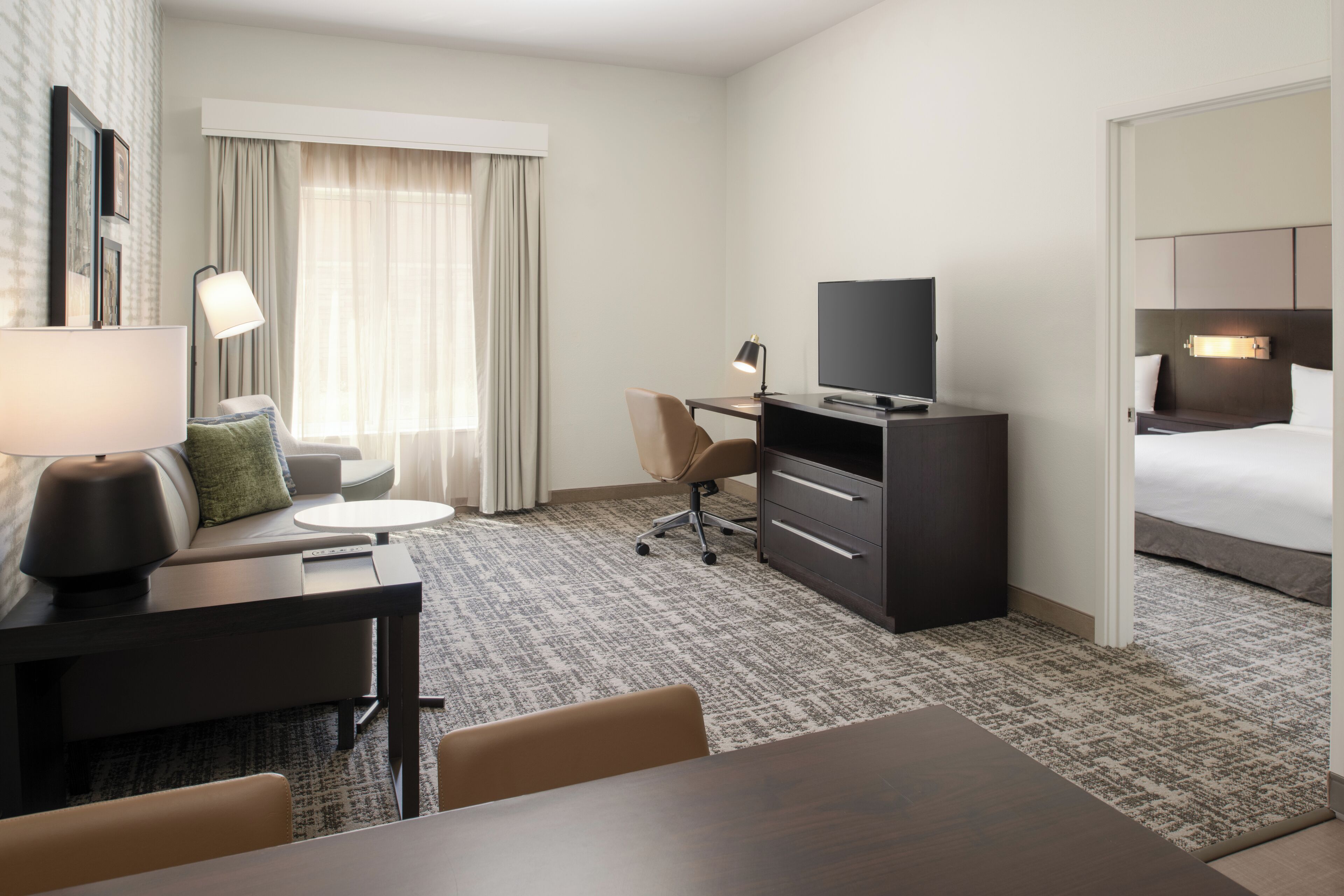 Une chambre d’hôtel comprenant un lit, un bureau avec un ordinateur, une chaise, une lampe et un téléviseur.