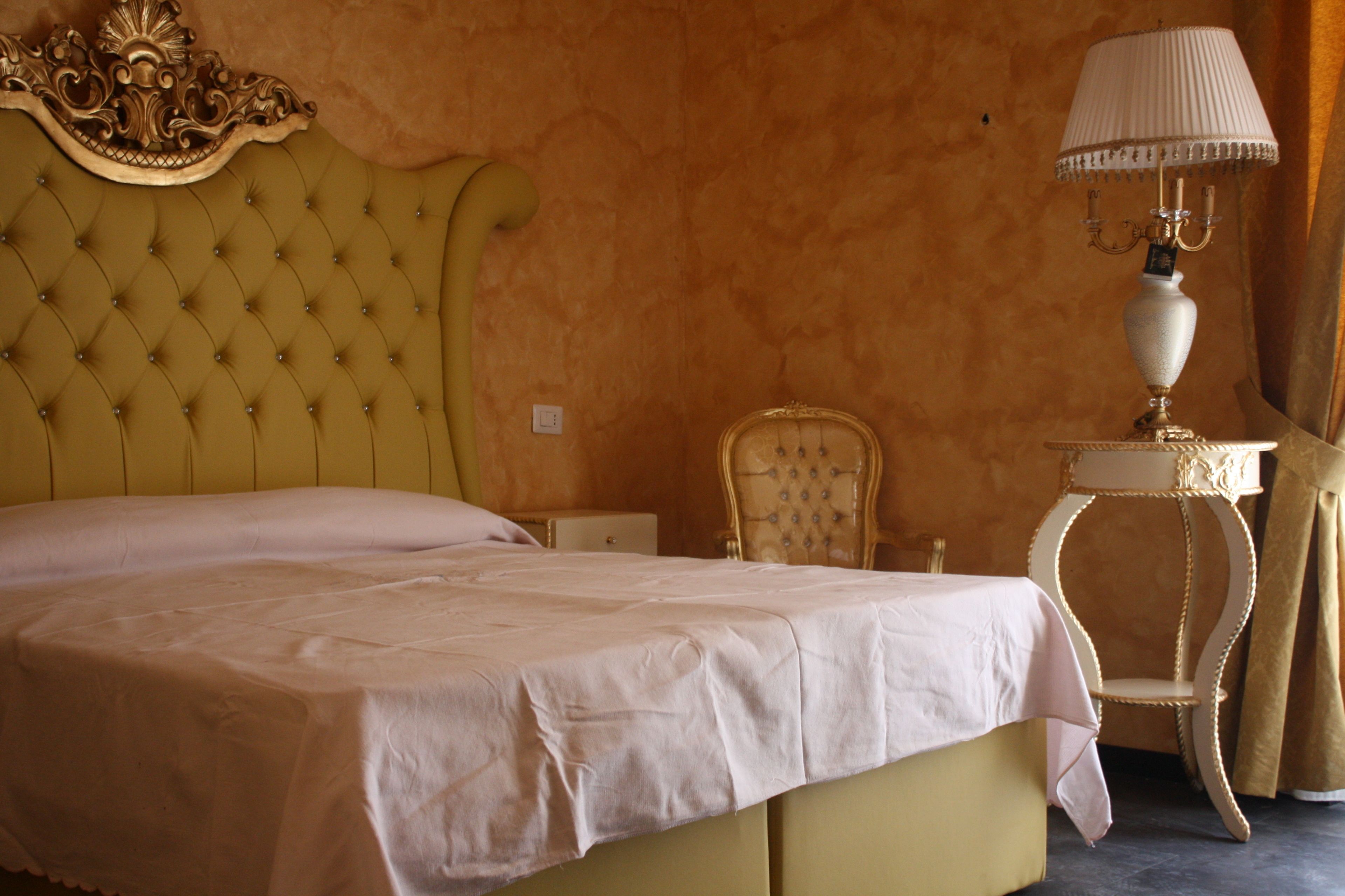 A bedroom with a large bed, a nightstand, a lamp, and a chair.