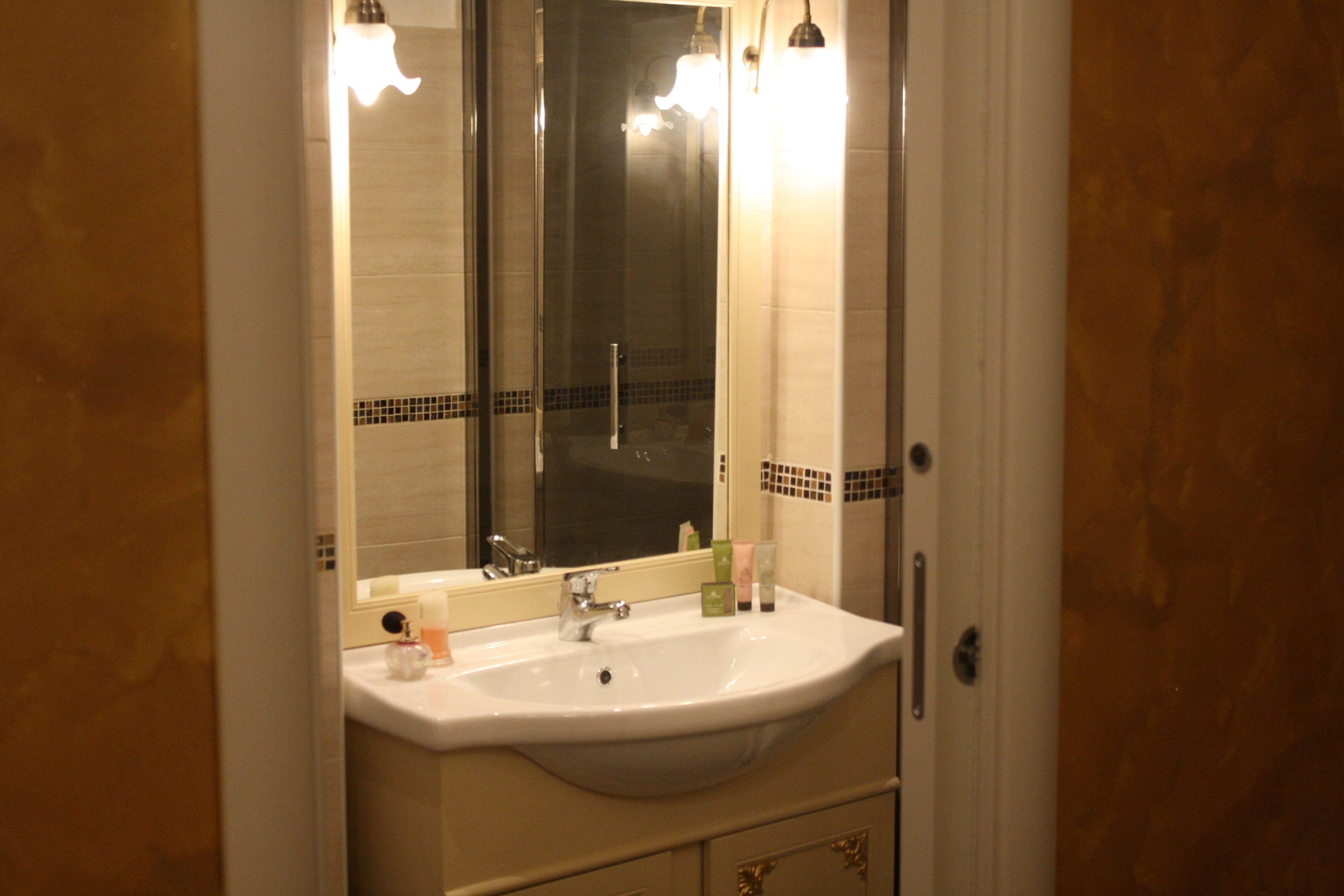A bathroom with a white sink, a mirror, and a door with a handle.