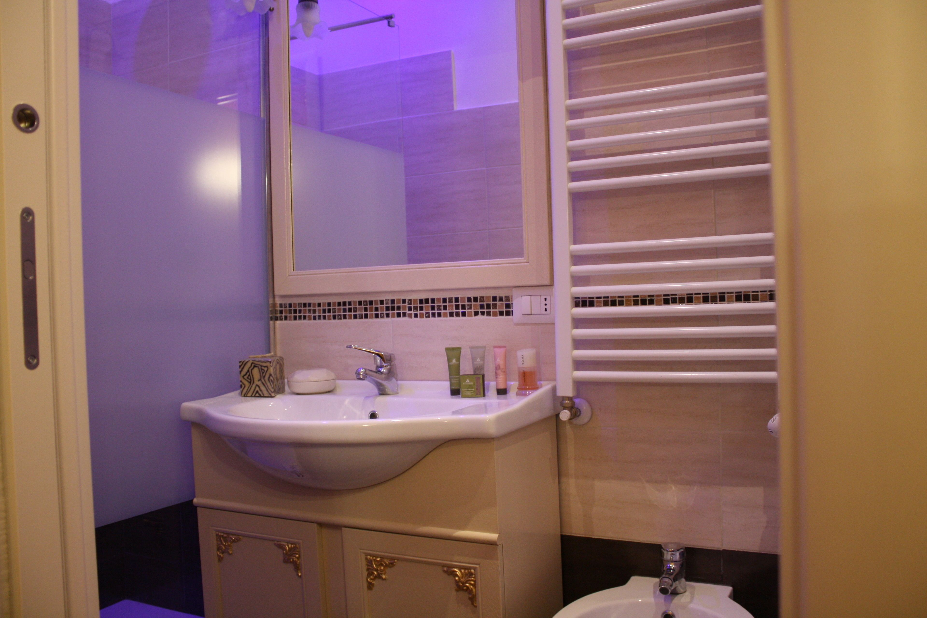 A bathroom with a sink, mirror, and towel rack.