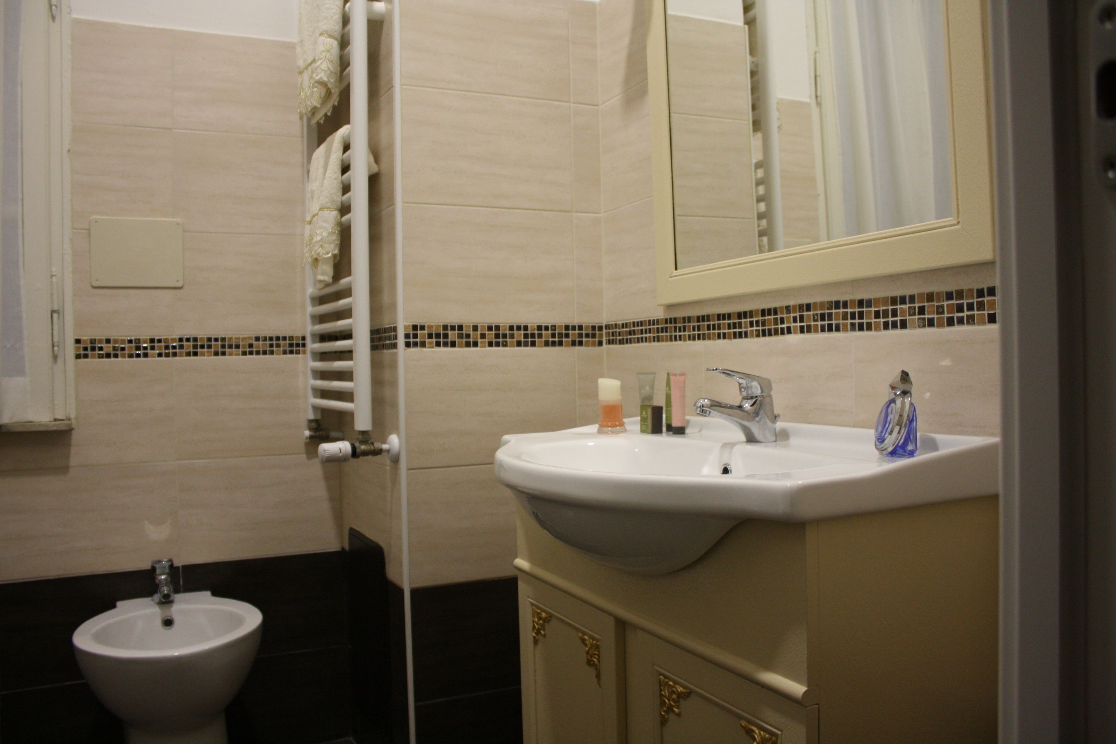 Een badkamer met een bidet, een wastafel en een spiegel.