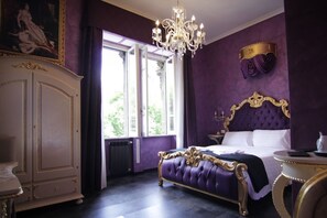 Um quarto luxuoso com uma cama grande, um candelabro e vista para o verde lá fora.