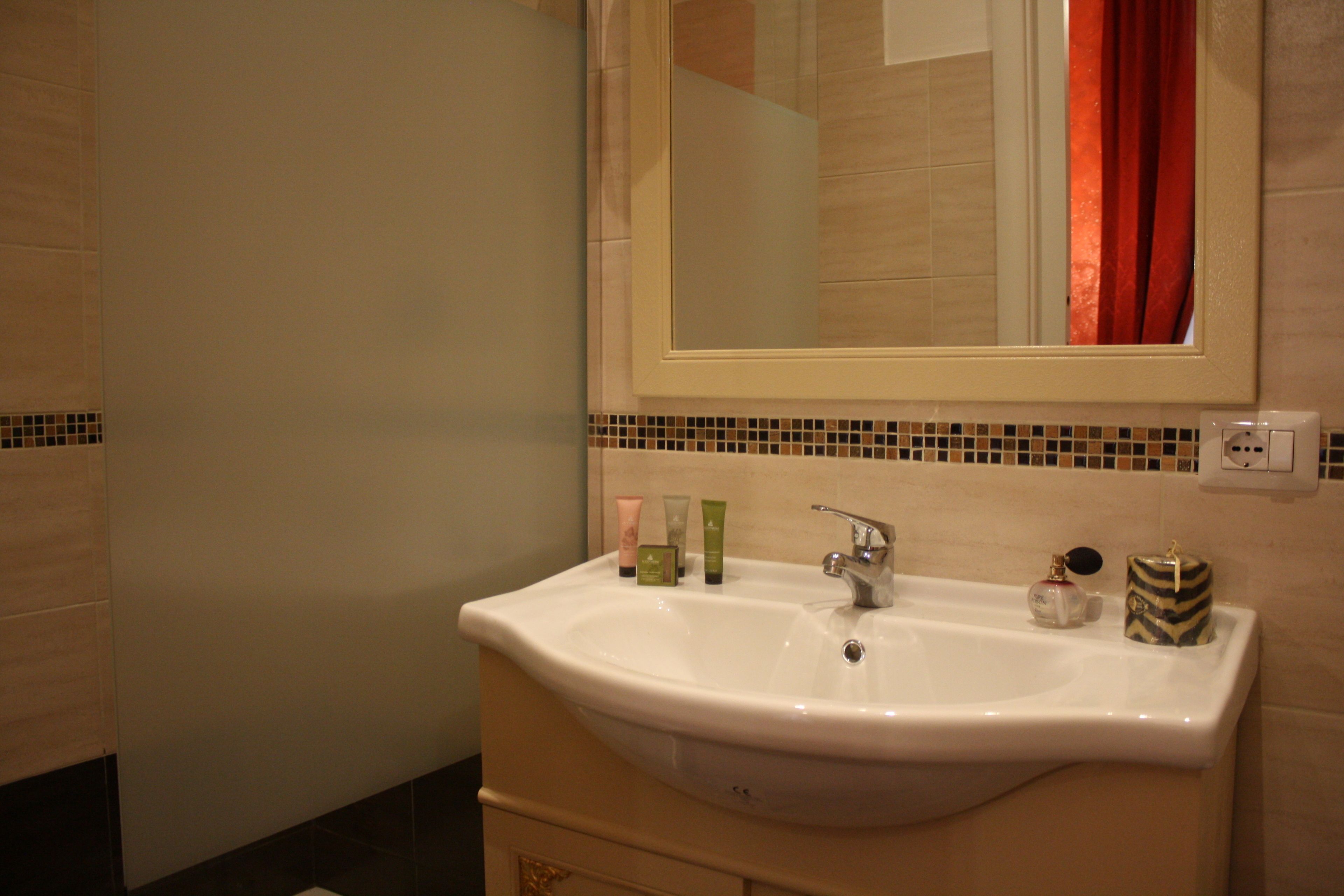 A bathroom with a white sink, a mirror, and toiletries on the counter.