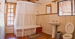 A bathroom with a shower, sink, toilet, and a window with a curtain. - Jafuta Lodge (Victoria Falls)