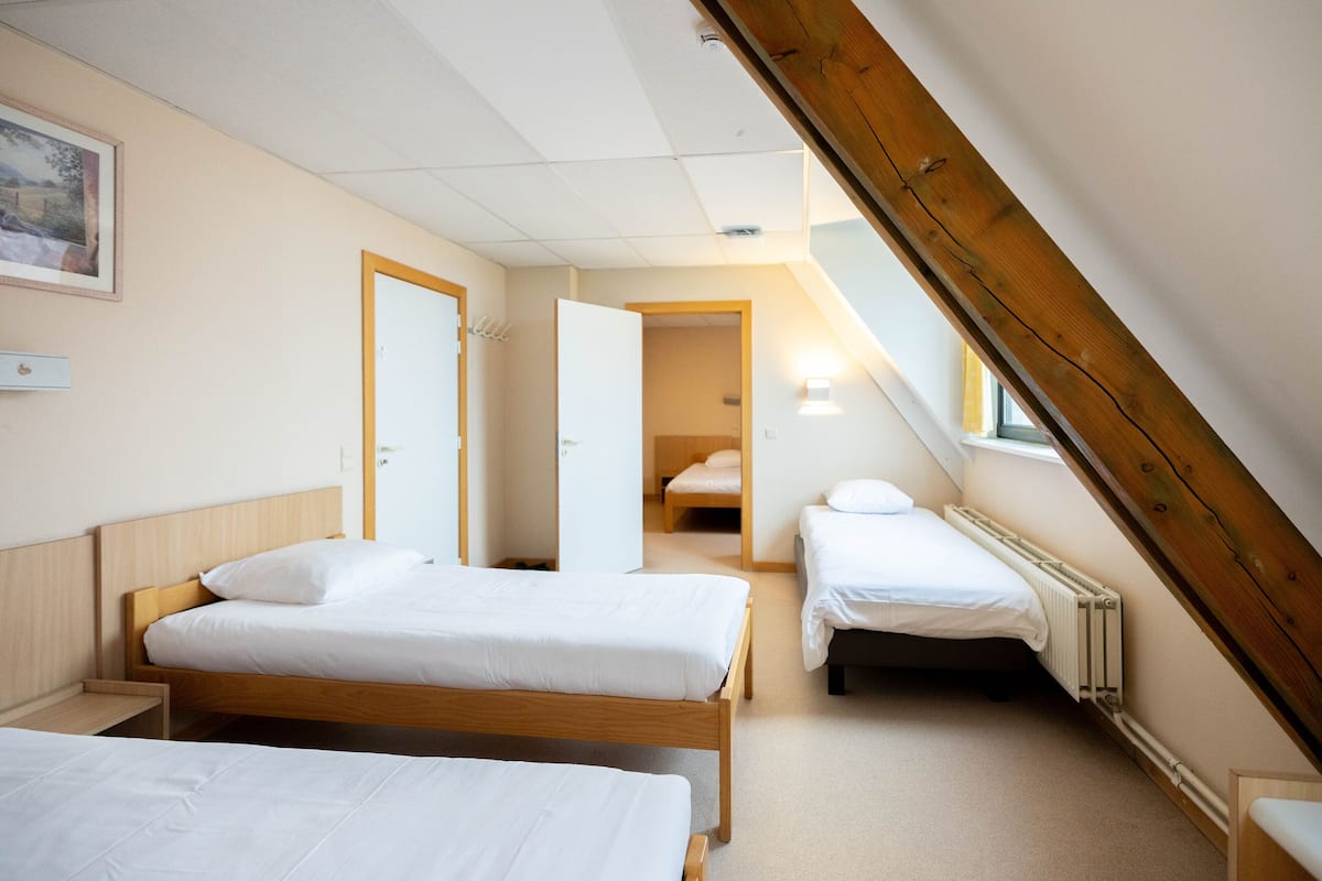 Une chambre avec deux lits, un plafond en bois et une vue sur un couloir.