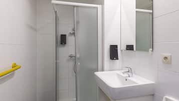 A modern bathroom with a glass shower enclosure, a white sink, and a mirror.