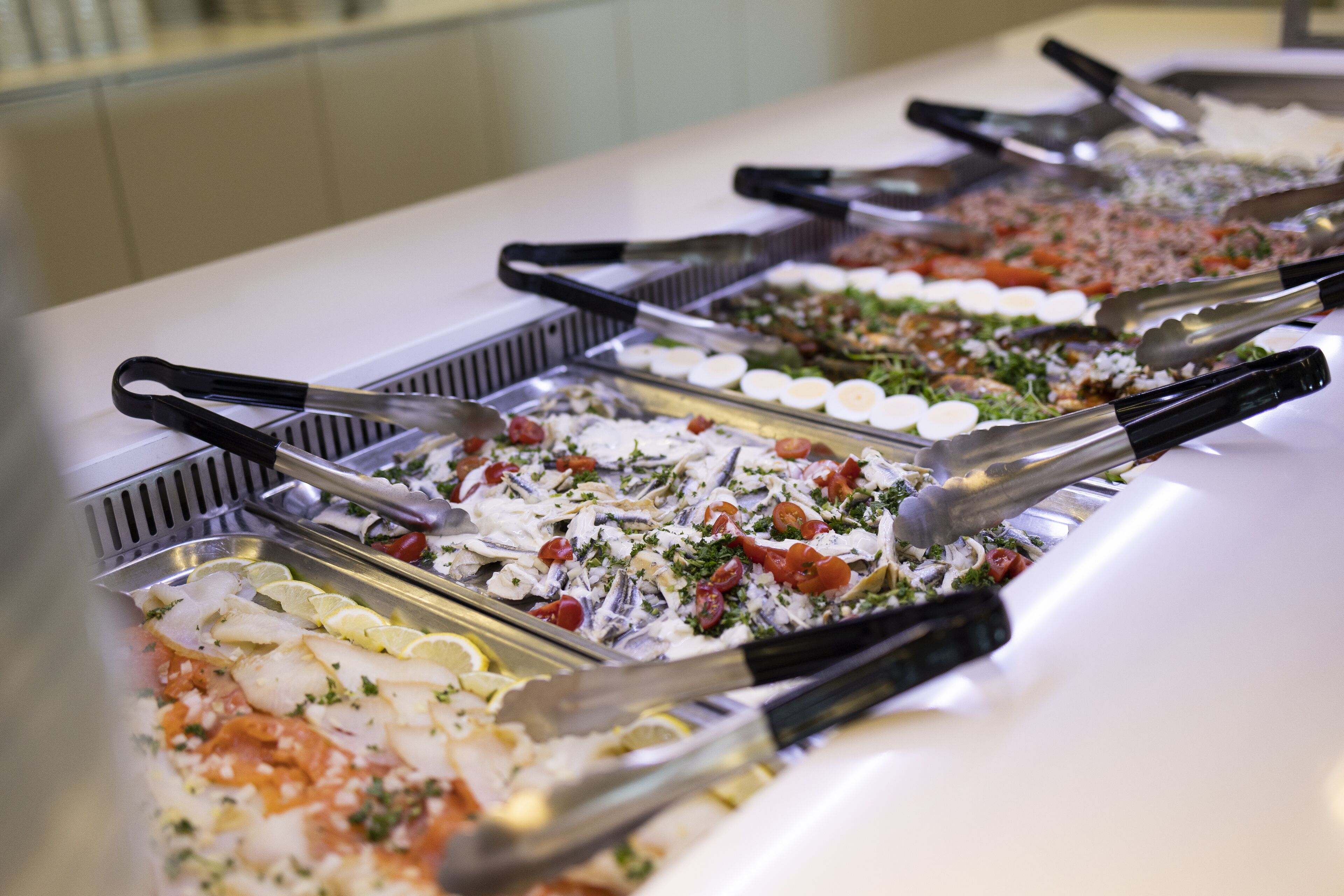 Buffet com diversos pratos, incluindo frutos do mar e saladas, e talheres.