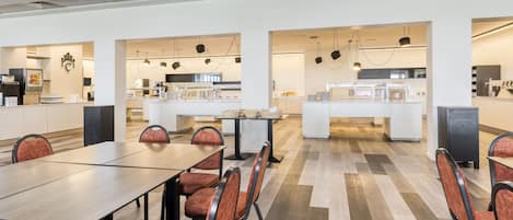 Un comedor moderno con una mesa larga y sillas, una zona de cocina con electrodomésticos, y un espacio limpio y bien iluminado.