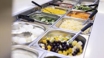Buffet com diversos alimentos, incluindo frutas, vegetais e cereais.