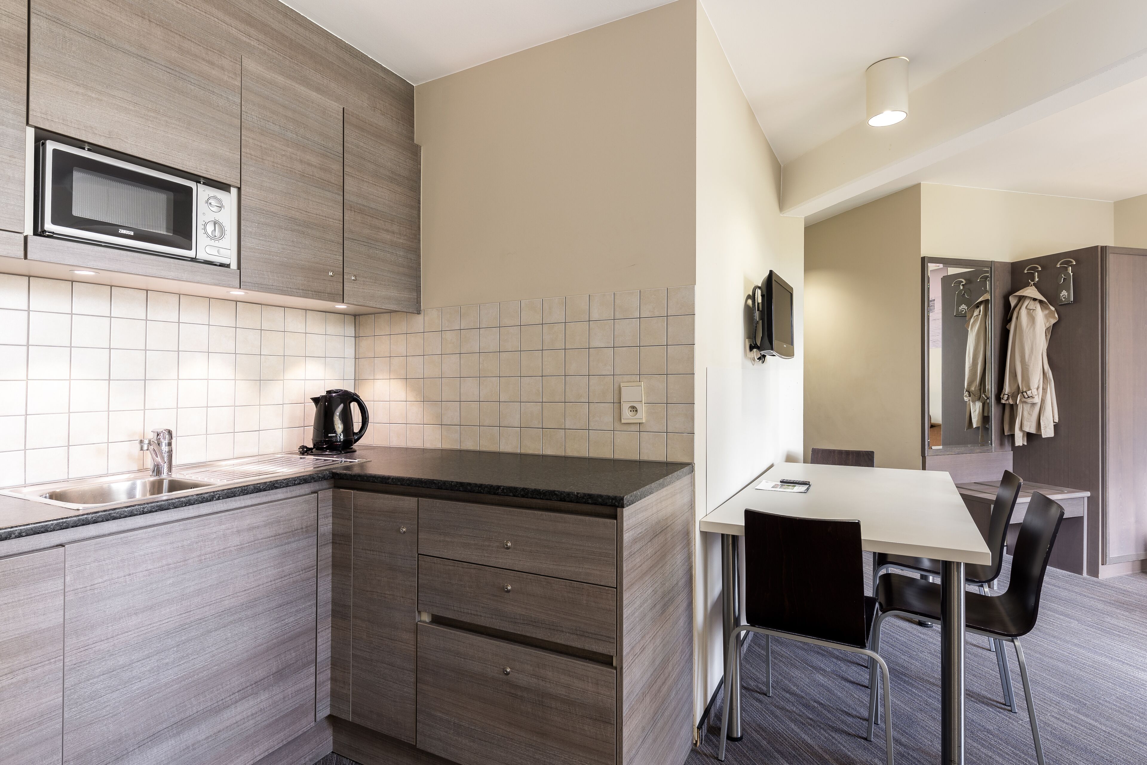 A modern kitchen with a microwave, sink, and a small dining area with a table and chairs.