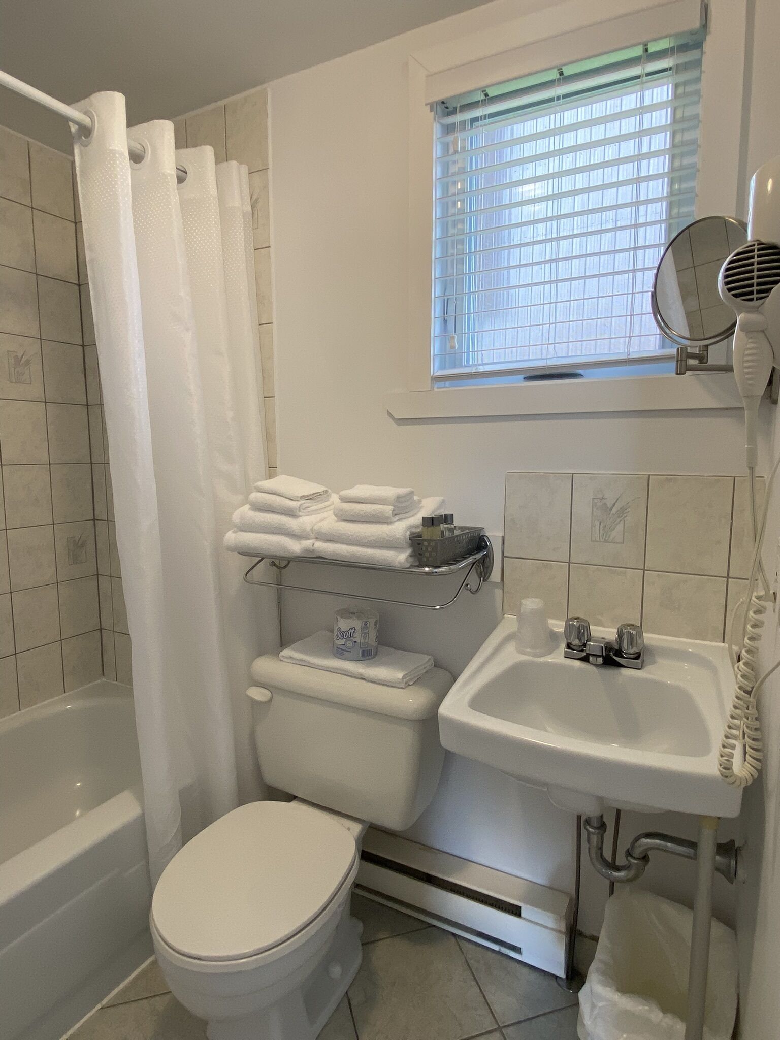 Un bagno con vasca, servizi igienici, lavandino e una finestra con persiane.