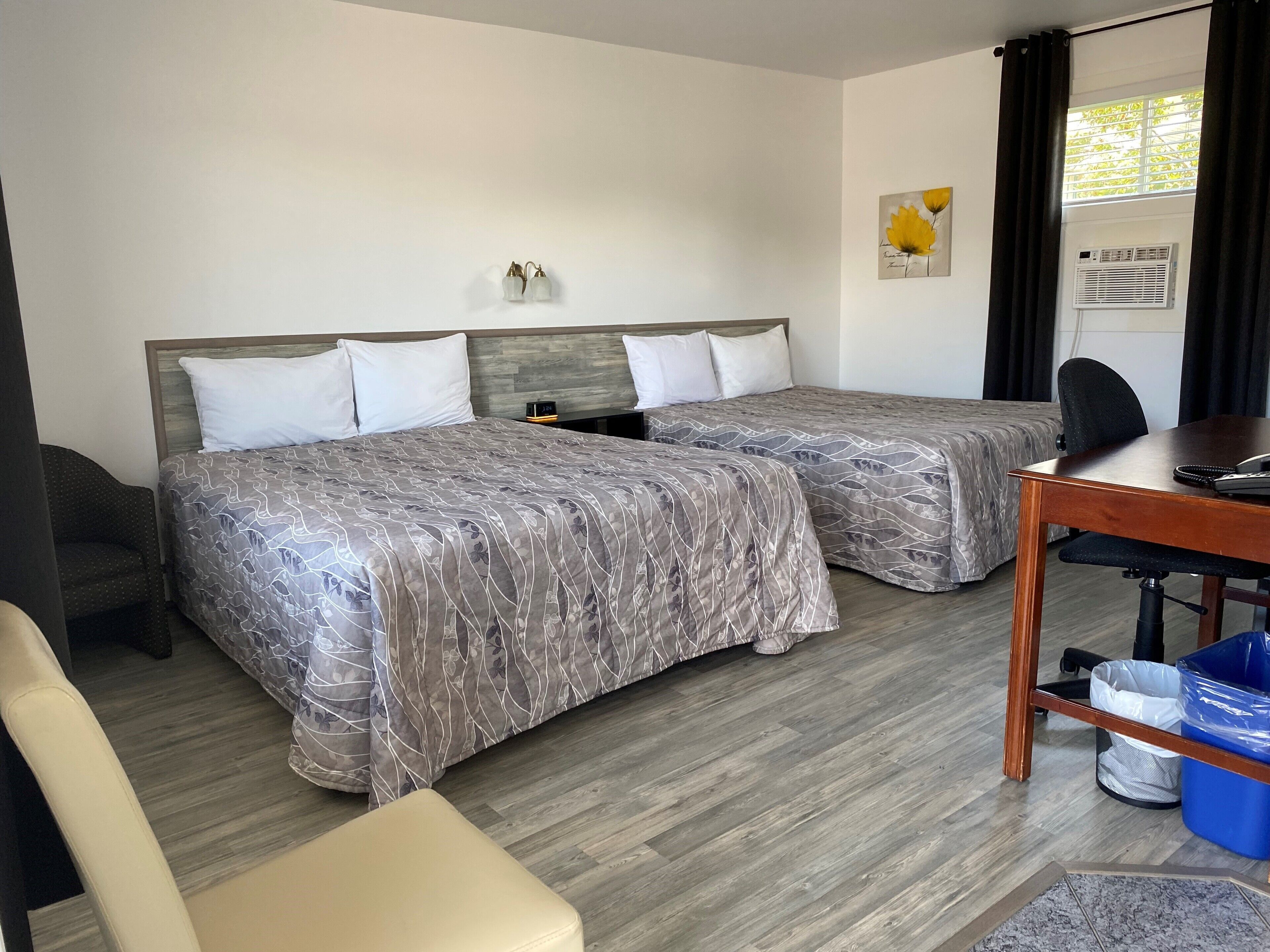 Una camera d'albergo con due letti, una scrivania, una sedia e un tavolino.