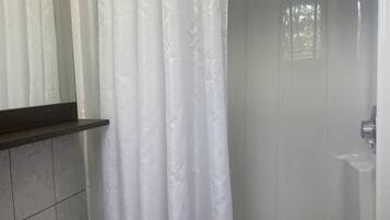A bathroom with a white sink, a shower with a white curtain, and a mirror above the sink.