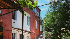 Une cour avec un bâtiment rouge, un escalier et des plantes en pot ornées de fleurs.