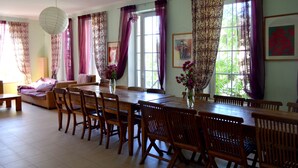 Un espace repas comprenant une longue table en bois, plusieurs chaises et deux vases ornés de fleurs.