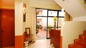 Un hall de hotel con puerta de madera, un inodoro, un sofá y una escalera.