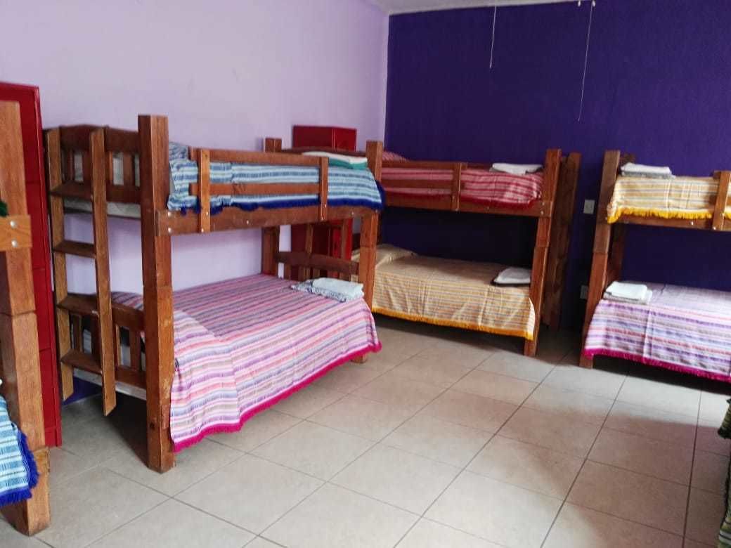 Un dormitorio con literas, piso de baldosas y pared morada.