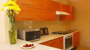 Una cocina moderna con armarios de madera, un microondas, un horno y un comedor con un jarrón de flores amarillas.