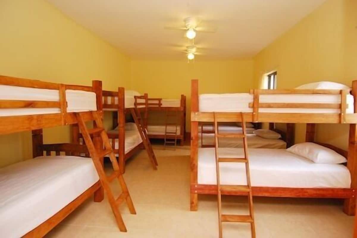 Um quarto de dormitório com beliches, móveis de madeira e um ventilador de teto.