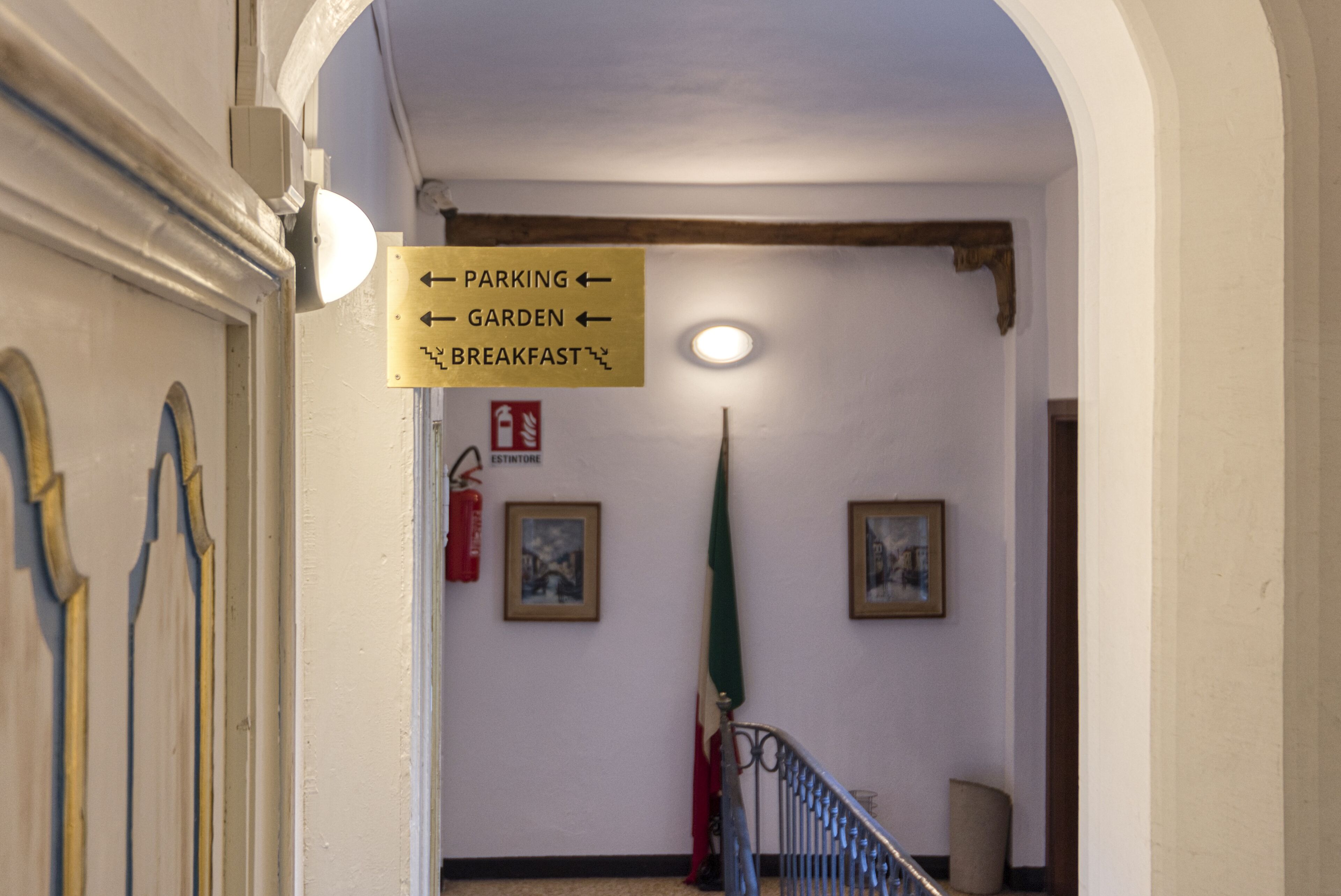 Un couloir avec un panneau indicateur indiquant l’emplacement du parking, du jardin et de la salle de petit-déjeuner.