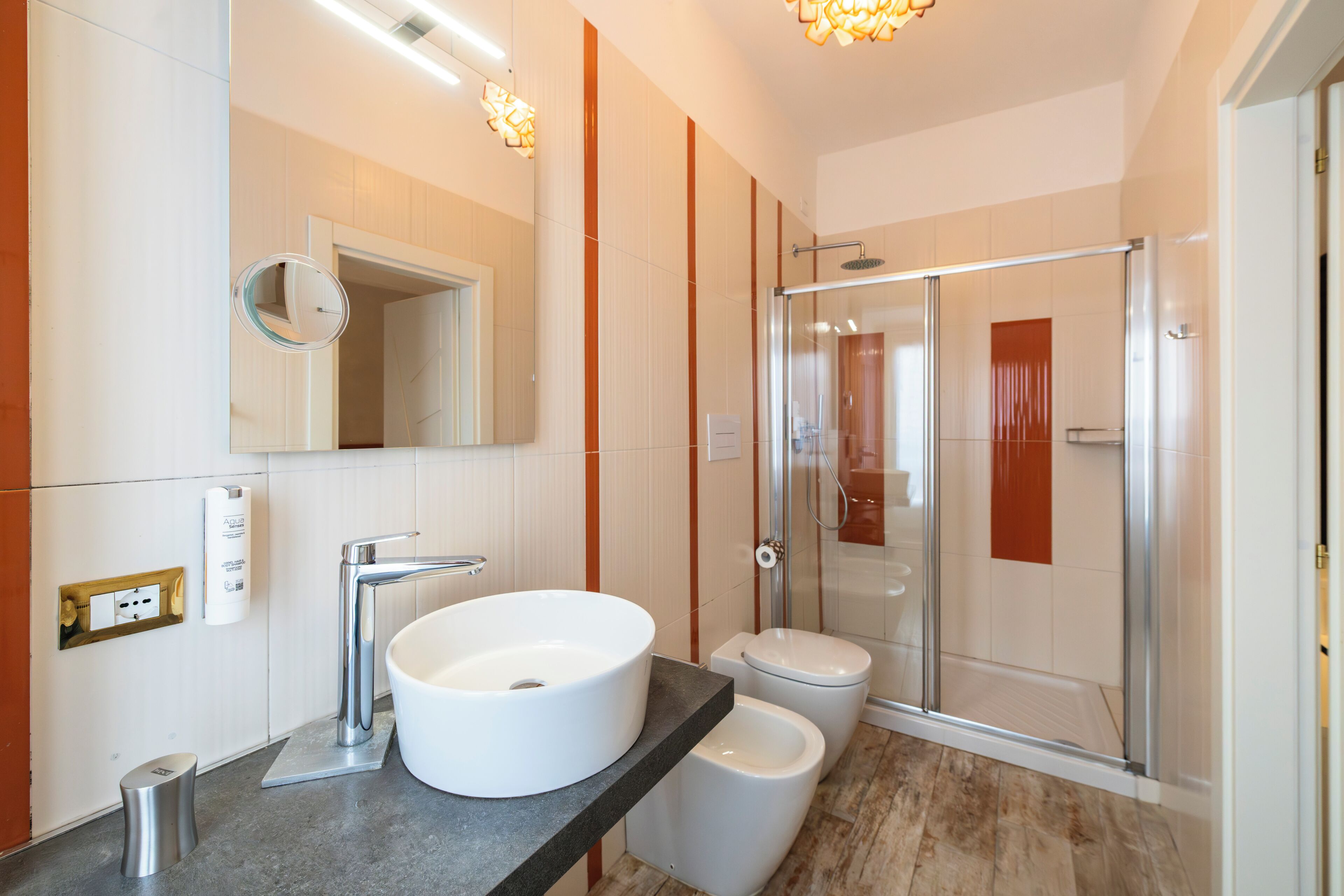 Un baño moderno con un lavamanos grande, inodoro y cabina de ducha de cristal.
