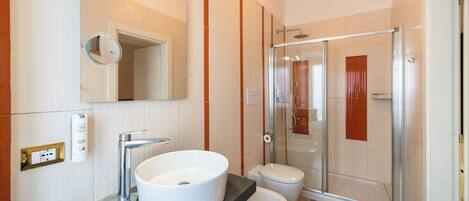 Un baño moderno con un lavamanos grande, inodoro y cabina de ducha de cristal.