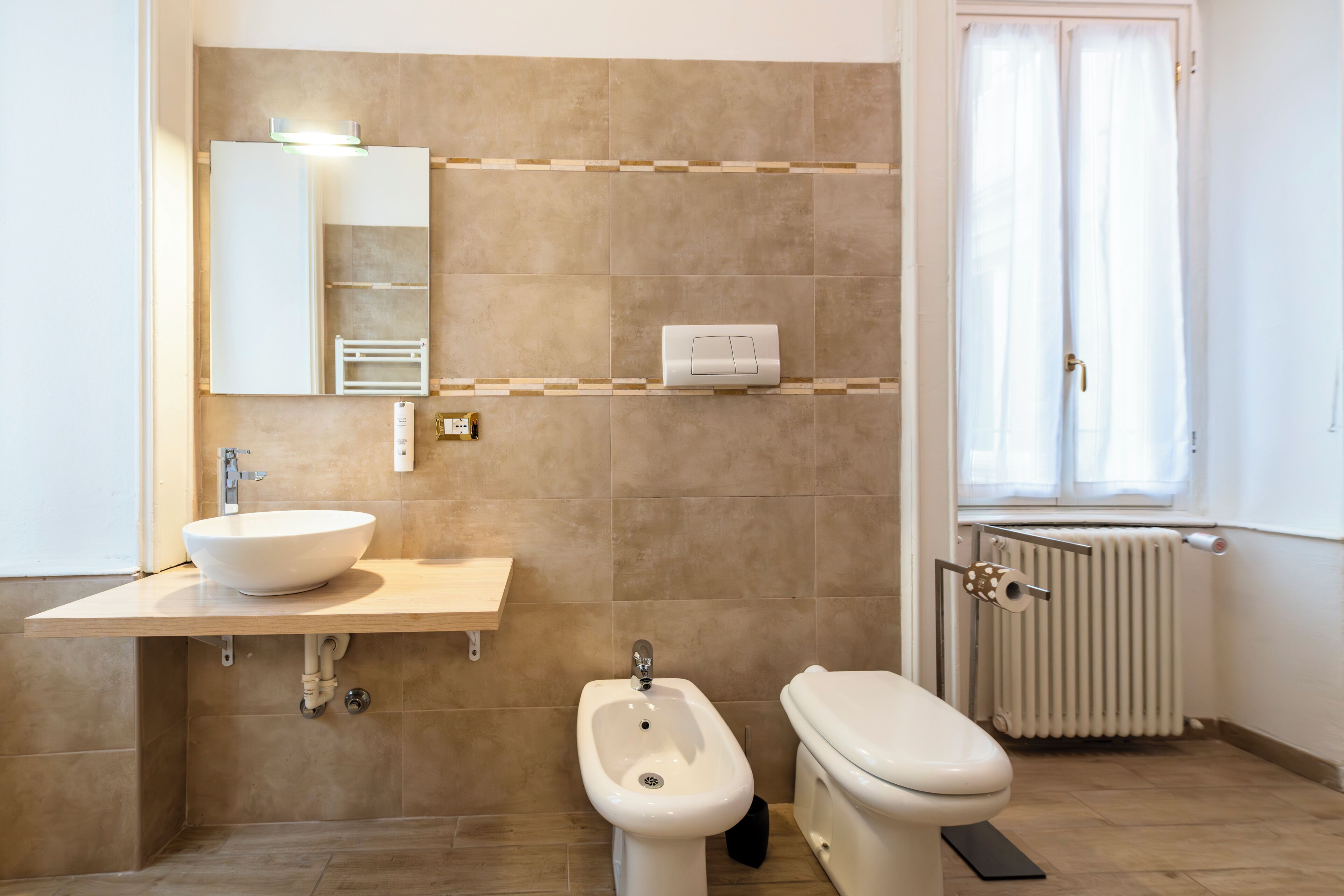 Een badkamer met een wastafel, bidet, toilet en een handdoekradiator.