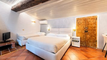 A bedroom with a large bed, a television, a wooden door, and a small shelf with items.