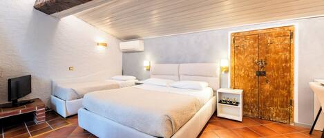 A bedroom with a large bed, a television, a wooden door, and a small shelf with items.