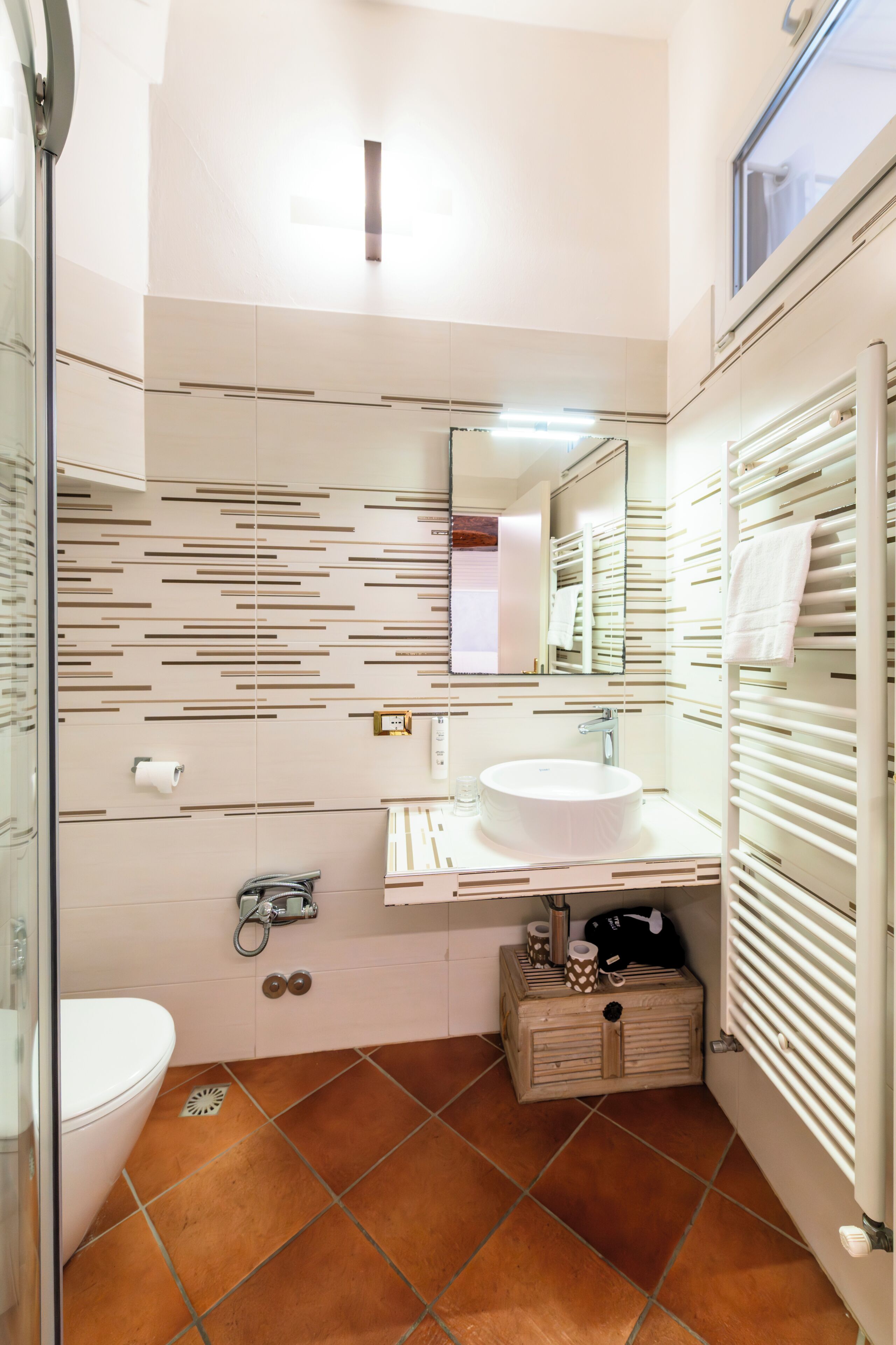 Un bagno con lavandino bianco, specchio e porta asciugamani.
