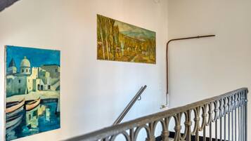 A staircase with ornate metal railings and two paintings on the wall.